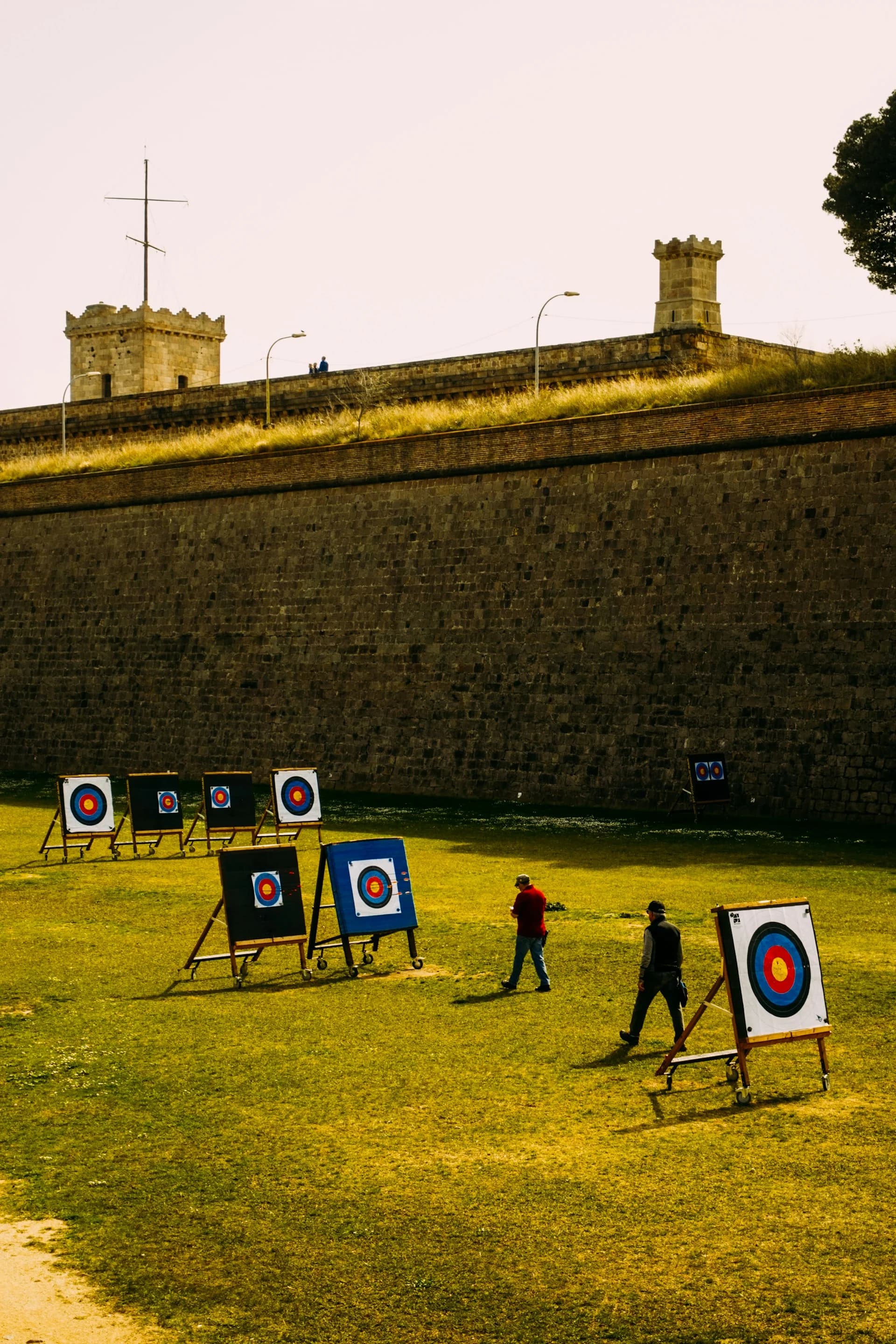 peoples walking to the targets in an archery range next to a fortress