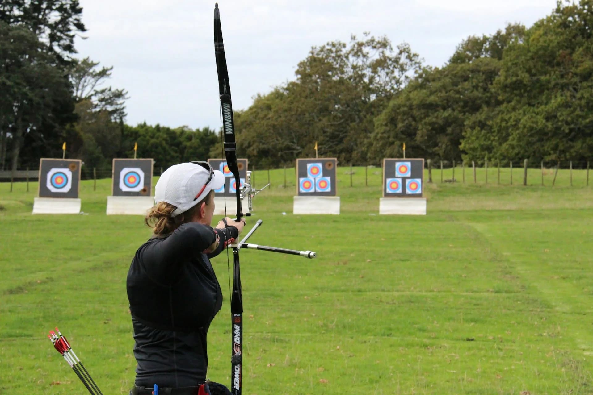 a woman ready to shoot with her bow in an archery range